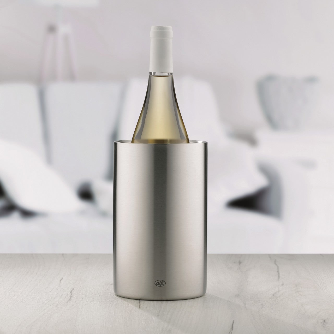 Die moderne Pendelleuchte hat einen metallischen, zylindrischen Körper und einen messingfarbenen Oberteil. Sie hängt in einem hellen Raum mit einem weißen Sofa im Hintergrund.
