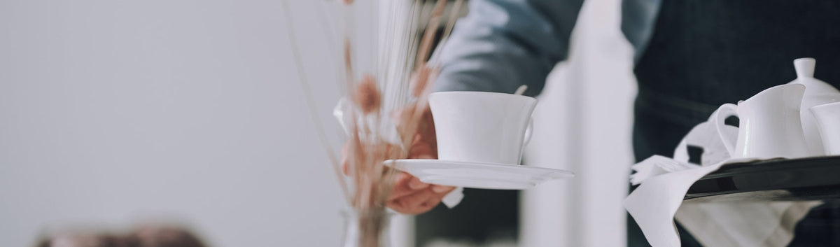 Mensch übergibt eine Tasse von einem Tablett in der Gastronomie